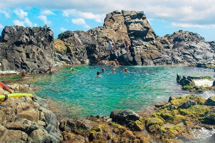 a group of people in a rocky area next to water