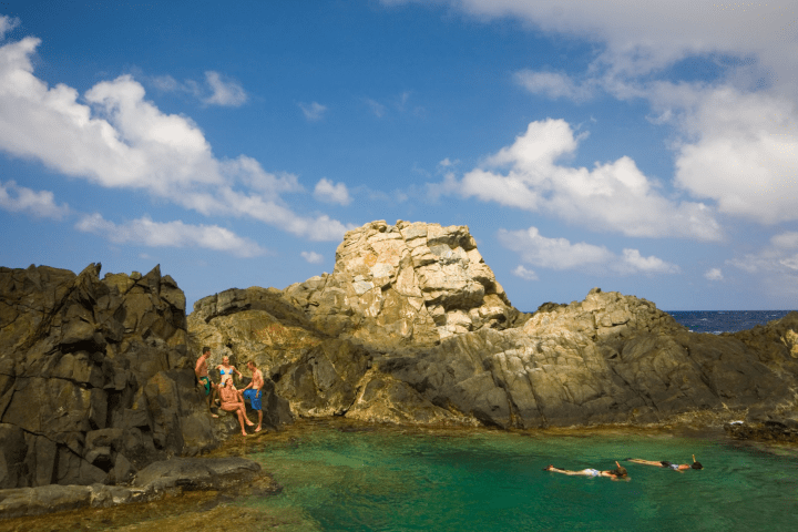 a group of people on a rock next to water
